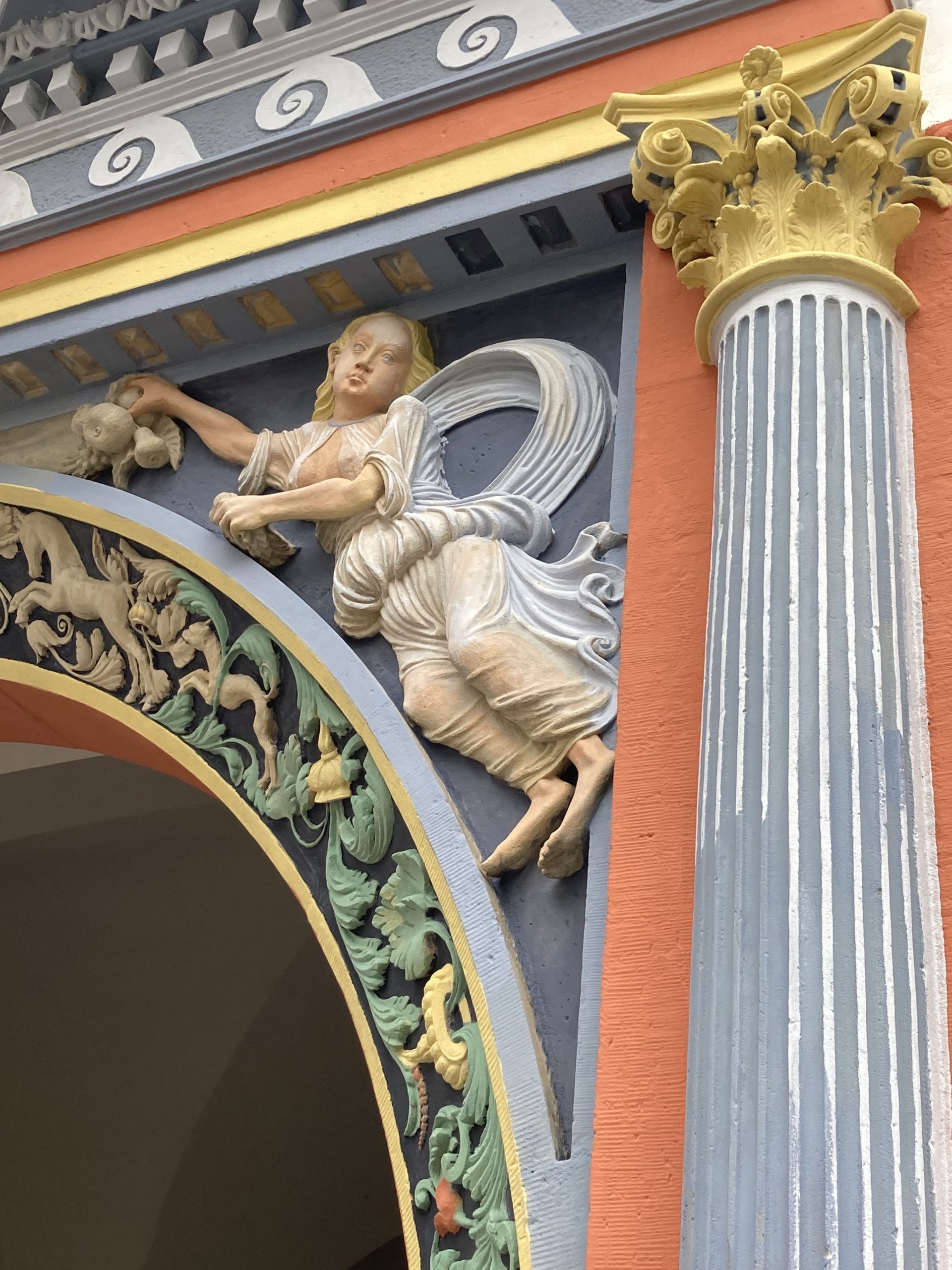 relief of an angel on an archway, the angel is almost completely restored (painted) and very lightly clad