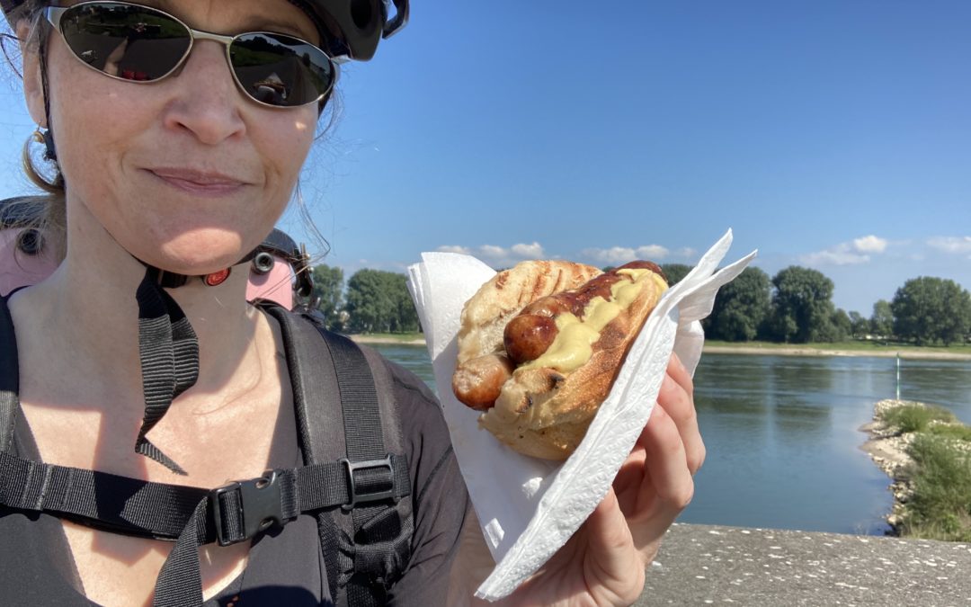 me in cycle gear eating a sausage with the Rhine in the background