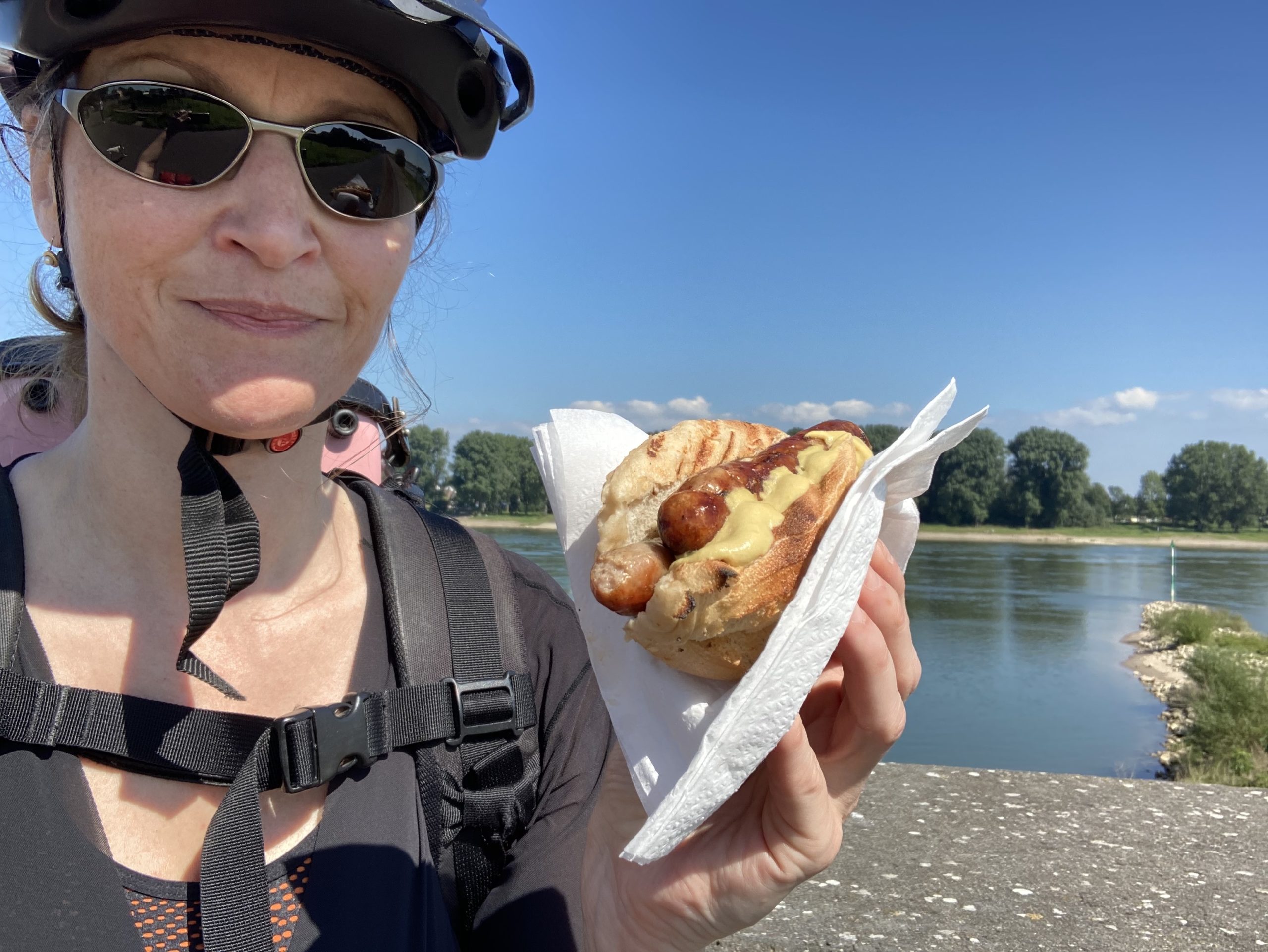 me in cycle gear eating a sausage with the Rhine in the background