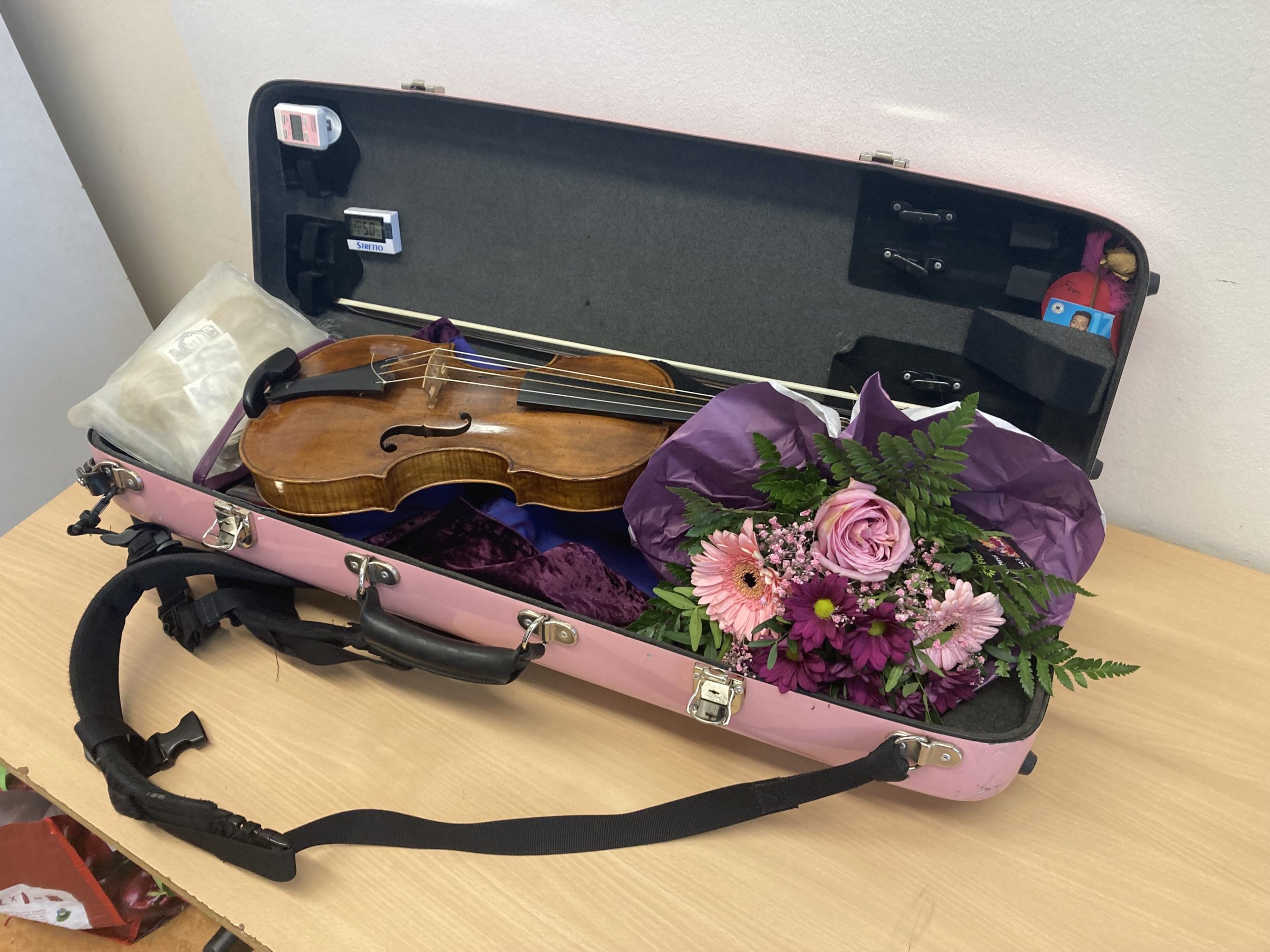 open pink violin case with violin and bouquet of pink flowers inside